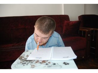 Kalemi ağzıyla tutuyor, sayfaları diliyle çeviriyor