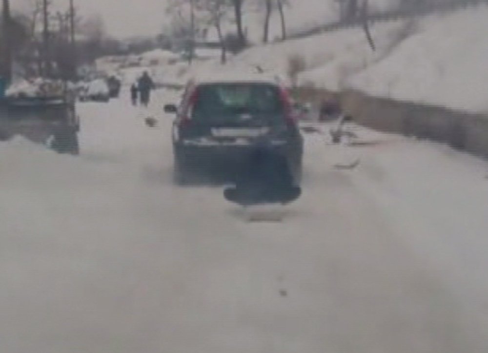 Otomobilin arkasında kızak keyfi ilginç görüntü oluşturdu